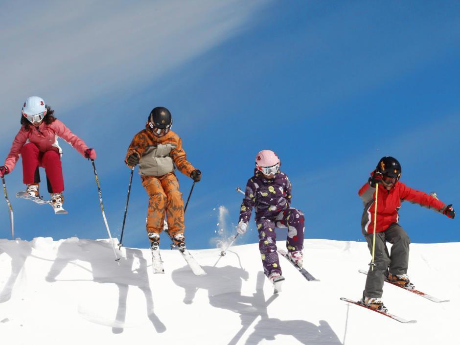 Vier Kinder springen beim Skifahren im Skigebiet Weissbriach über eine Anhöhe auf der Skipiste. JUFA Hotels bietet erholsamen Familienurlaub und einen unvergesslichen Winterurlaub.