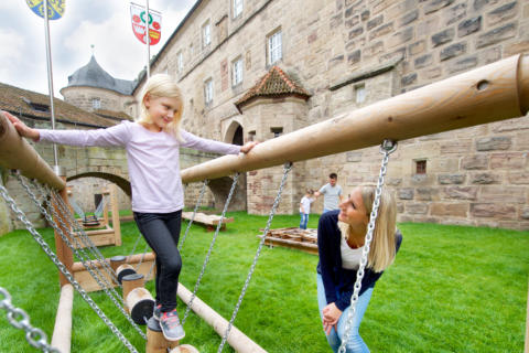 Sie sehen Kinder beim Spielen auf dem Spielplatz des JUFA Hotel Kronach – Festung Rosenberg***. Der Ort für kinderfreundlichen und erlebnisreichen Urlaub für die ganze Familie.