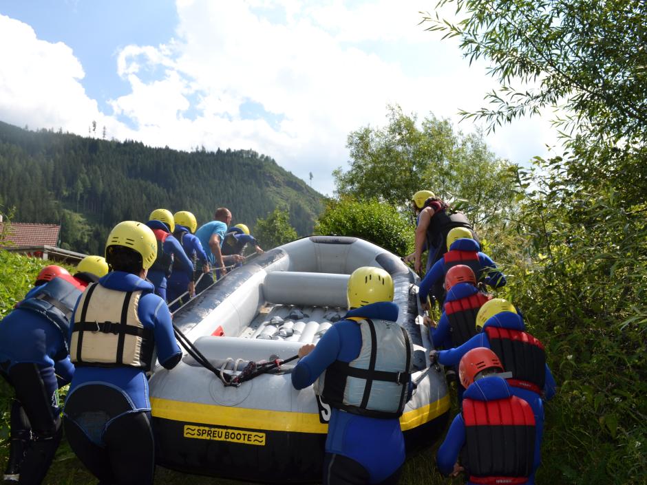 Kindergruppe mit Rafting-Schlauchboot vor dem Start ins Abenteuer. JUFA Hotels bietet erlebnisreiche Feriencamps in den Bereichen Sport, Gesundheit, Bildung und Sprachen.