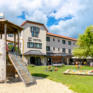 Sie sehen das JUFA Hotel Lipizzanerheimat von Aussen mit Garten und Spielplatz. JUFA Hotels bietet kinderfreundlichen und erlebnisreichen Urlaub für die ganze Familie.