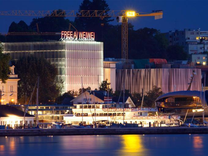 Sie sehen das Kunsthaus Bregenz bei Nacht vom Bodensee aus.JUFA Hotels bietet erlebnisreichen Städtetrip für die ganze Familie und den idealen Platz für Ihr Seminar.