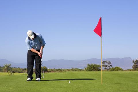 Mann beim Golfen auf Golfplatz im Sommer in der Nähe von JUFA Hotels. Der Ort für erlebnisreichen Natururlaub für die ganze Familie.