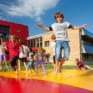 Kinder hüpfen auf Hüpfburg im Outdoorspielbereich vom JUFA Hotel Bleiburg – Sport-Resort. Der Ort für erholsamen Familienurlaub und einen unvergesslichen Winter- und Wanderurlaub.