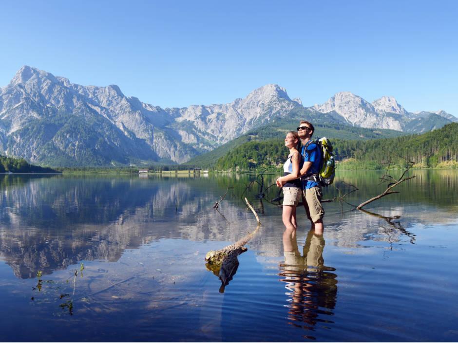 Ein junges Paar steht umarmend im Sommer im Almsee in Oberösterreich. JUFA Hotels bietet Ihnen den Ort für erlebnisreichen Natururlaub für die ganze Familie.
