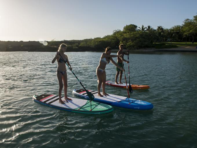 Sie sehen drei Personen beim Stand Up-Paddling am See. JUFA Hotels bietet tollen Sommerurlaub an schönen Seen für die ganze Familie.