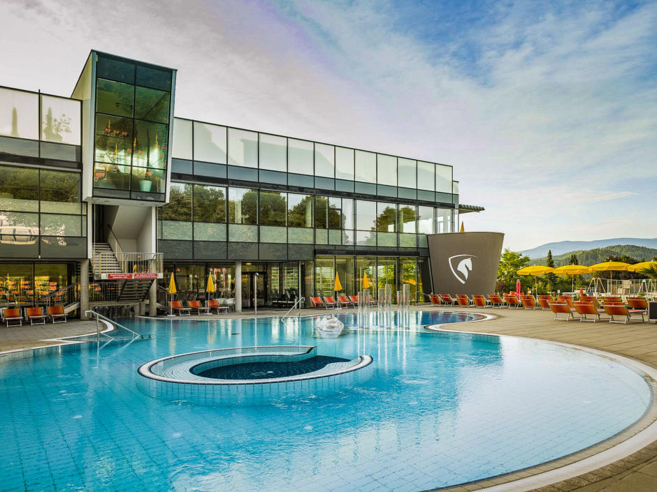 Sie sehen den Außenbereich der Therme Nova im Sommer, das große runde Pool lädt zum Schwimmen ein. JUFA Hotels bietet erholsamen Familienurlaub und einen unvergesslichen Winter- und Wanderurlaub.