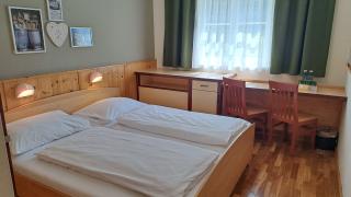 Sie sehen ein Bild vom Low Budget 2 Zimmer mit Doppelbett, Wanddeko und Tisch mit Sessel im JUFA Hotel Bad Aussee*** in der Steiermark.