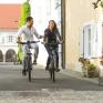 Sie sehen einen Mann und eine Frau beim Radfahren in der Altstadt von Bad Radkersburg in der Nähe vom JUFA Hotel Bad Radkersburg.