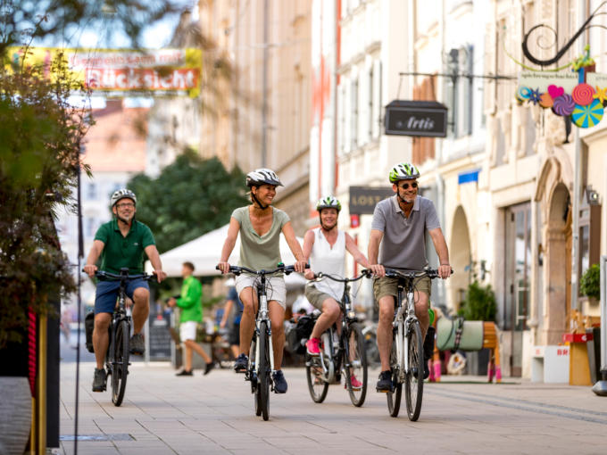 Sie sehen vier Radfahrer in Graz. JUFA Hotels bietet erholsamen Familienurlaub und einen unvergesslichen Winterurlaub