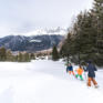 Sie sehen eine Familie beim Schneeschuhwandern in Savognin. JUFA Hotels bietet erholsamen Familienurlaub und einen unvergesslichen Winterurlaub.