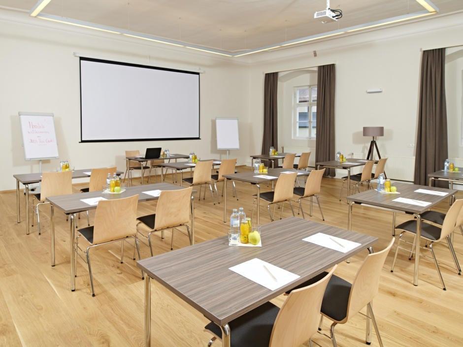 Sie sehen einen gut ausgestatteten Seminarraum mit Beamerwand im JUFA Hotel Stift Gurk. Der Ort für erfolgreiche und kreative Seminare in abwechslungsreichen Regionen.