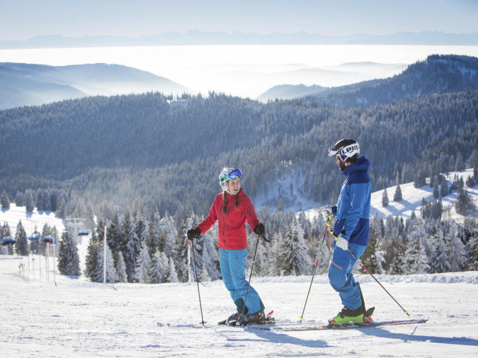 Sie sehen 2 Personen beim Skifahren am Feldberg im Schwarzwald.