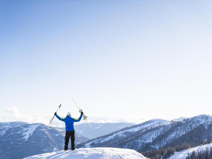 Sie sehen einen Skifahrer auf einem Gipfel in St. Oswald im Winter. JUFA Hotels bietet erholsamen Familienurlaub und einen unvergesslichen Winterurlaub.
