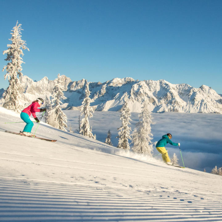 Sie sehen zwei Skifahrer am Hochwurzen in Schladming-Dachstein. JUFA Hotels bietet erholsamen Familienurlaub und einen unvergesslichen Winterurlaub.
