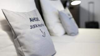 Sie sehen Kissen auf dem Bett in einem Hotelzimmer. JUFA Hotels bietet kinderfreundlichen und erlebnisreichen Urlaub für die ganze Familie.