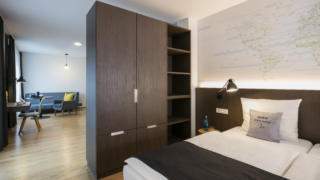 Sie sehen eine Suite mit Trennung der beiden Schlafbereiche im JUFA Hotel Hamburg HafenCity. 
