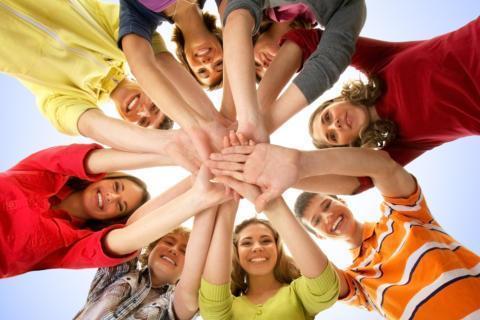 Teens bilden einen Kreis und legen ihre Hände übereinander als Zeichen für den Zusammenhalt in der Gruppe. JUFA Hotels bietet starkes und kreatives Teambuildung in abwechslungsreichen Regionen.