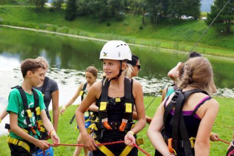 Sie sehen Teenager in professioneller Kletterausrüstung im Outdoorparc Lungau im Sommer. JUFA Hotels bietet erlebnisreiche Feriencamps in den Bereichen Sport, Gesundheit, Bildung und Sprachen.