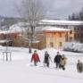 Teenager wandern durch Tiefschnee auf der verschneiten Wiese vorm JUFA Hotel Mariazell Sigmundsberg. Der Ort für erholsamen Familienurlaub und einen unvergesslichen Winter- und Wanderurlaub.