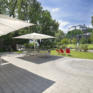 Sie sehen die Terrasse mit Gartenliege und Sonnenschirm im JUFA Hotel Salzburg City. Der Ort für erlebnisreichen Städtetrip für die ganze Familie und der ideale Platz für Ihr Seminar.