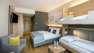 Sie sehen die Übersicht eines Familienzimmers FF4 mit Doppelbett und Etagenbett im JUFA Hotel Weiz. Der Ort für kinderfreundlichen und erlebnisreichen Urlaub für die ganze Familie.