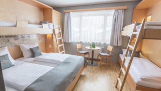Sie sehen ein Vierbettzimmer im JUFA Hotel Montafon. Der Ort für erholsamen Familienurlaub und einen unvergesslichen Winter- und Wanderurlaub.