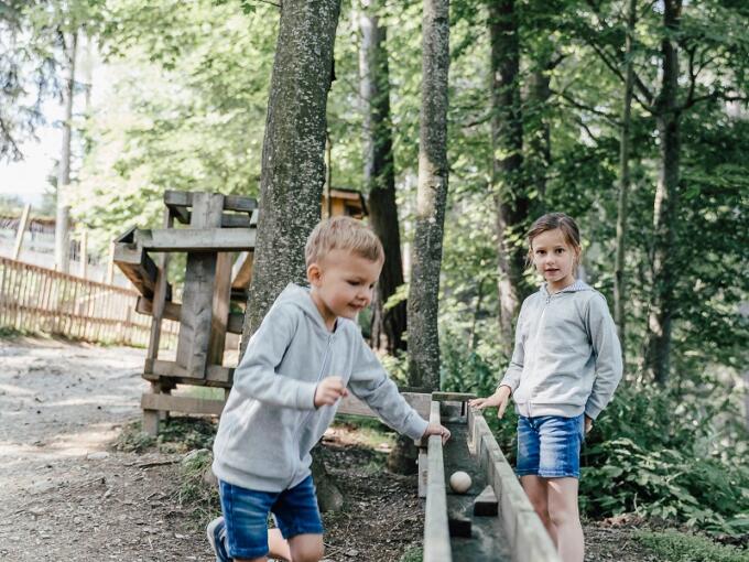 Sie sehen zwei Kinder beim Spielen auf der Kugelbahn im Waldpark Hochreiter.