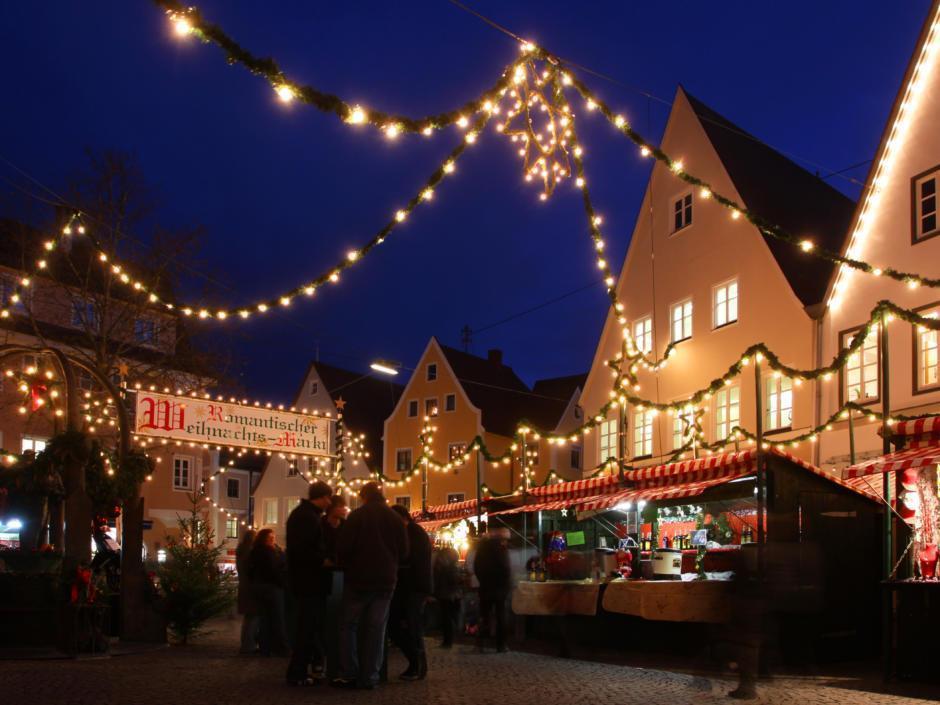 Sie sehen den Weihnachtsmarkt in Nördlingen am Abend mit Altstadthäusern. JUFA Hotels bietet erholsamen Familienurlaub und einen unvergesslichen Winter- und Wanderurlaub.