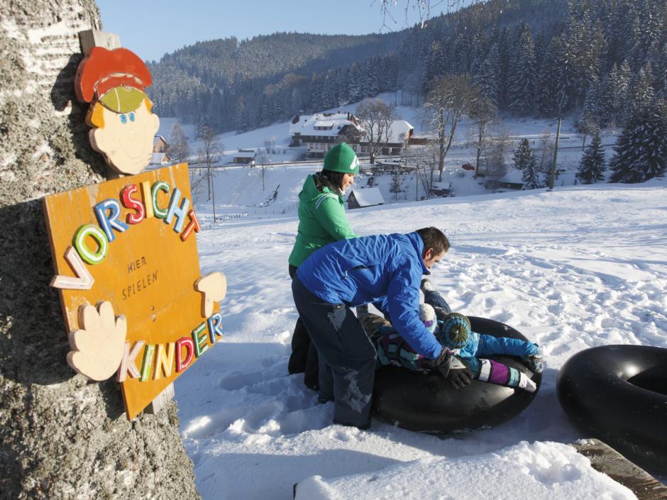 Sie sehen eine Familie beim Snowtubing im Schwarzwald.