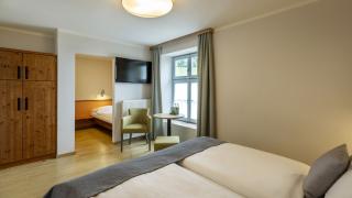 Sie sehen ein Einzelbett mit Holzschrank im Appartement im JUFA Hotel Schilcherland*** in der Steiermark.