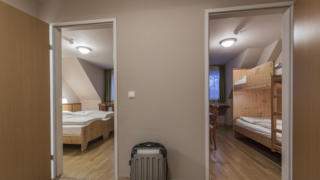 Sie sehen zwei Zimmer in einem Appartement 5xlarge im JUFA Hotel Grundlsee*** mit einem Koffer. JUFA Hotels bietet erholsamen Familienurlaub und einen unvergesslichen Winter- und Wanderurlaub.