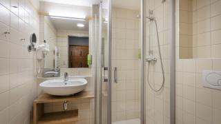 Sie sehen ein modernes Badezimmer im Doppelzimmer superior mit Dusche, WC, Waschbecken und großem Spiegel im JUFA Hotel Schilcherland*** in der Steiermark.