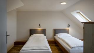Sie sehen zwei Einzelbetten im Oberstock eines Galeriezimmers für fünf Personen mit Dachfenster im JUFA Hotel Schilcherland*** in der Steiermark.
