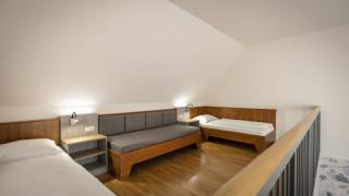 Sie sehen den oberen Stock eines Galeriezimmers für fünf Personen im JUFA Hotel Schilcherland*** mit zwei Einzelbetten und einer gemütlichen Schlafcouch.