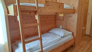 Sie sehen ein Etagenbett aus Holz im LowBudget 4 Zimmer im JUFA Hotel Bad Aussee*** im Salzkammergut.